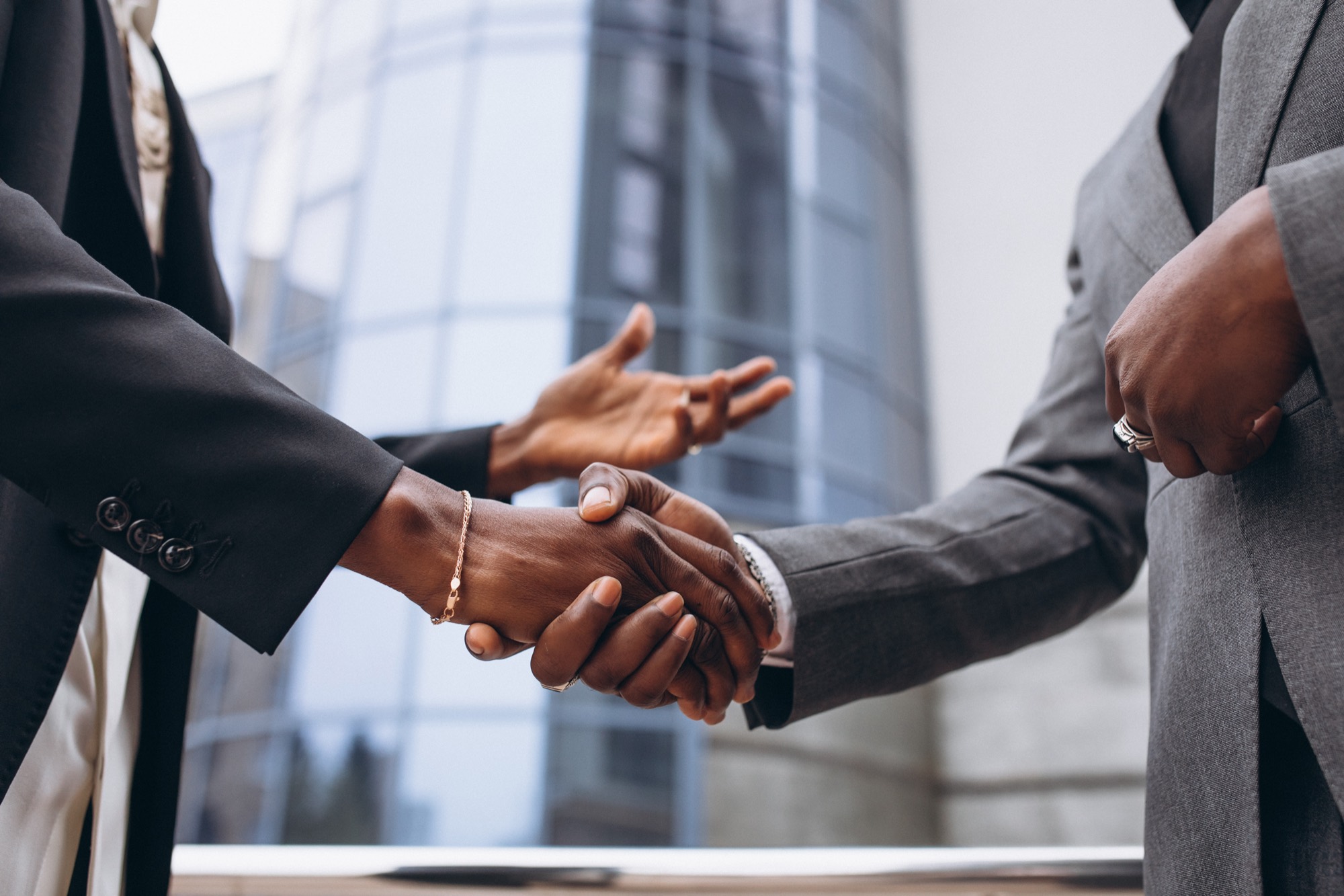 Poignée de main entre deux professionnels devant un immeuble de bureaux